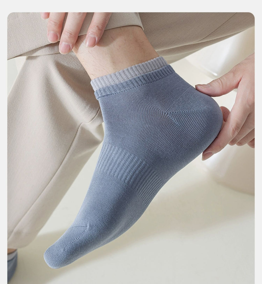Close-up of a man's foot wearing light blue ankle socks and beige pants