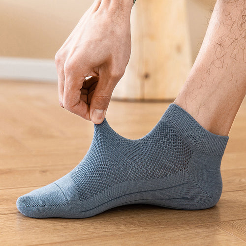 Man wearing blue breathable ankle socks, stretching fabric, wooden floor background